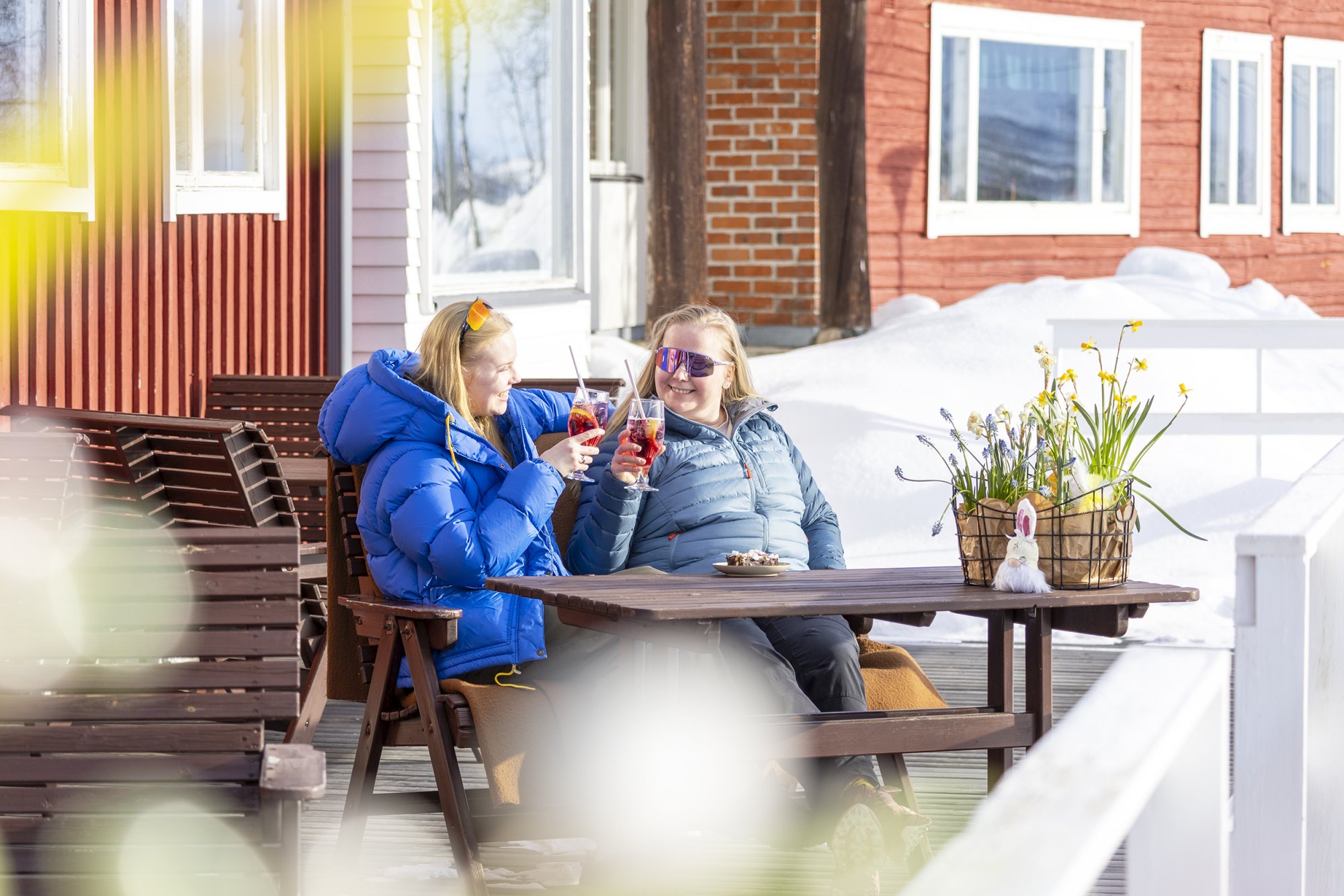 Two ladies enjoying the sun and drinks on the sunny terrace of Kilpisjärven Retkeilykeskus and restaurant Saana