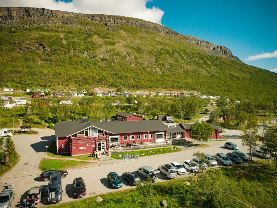 Kilpisjärven Retkeilykeskus right at the foot of Laplands most famous fell, Saana. It is sunny and it is green.