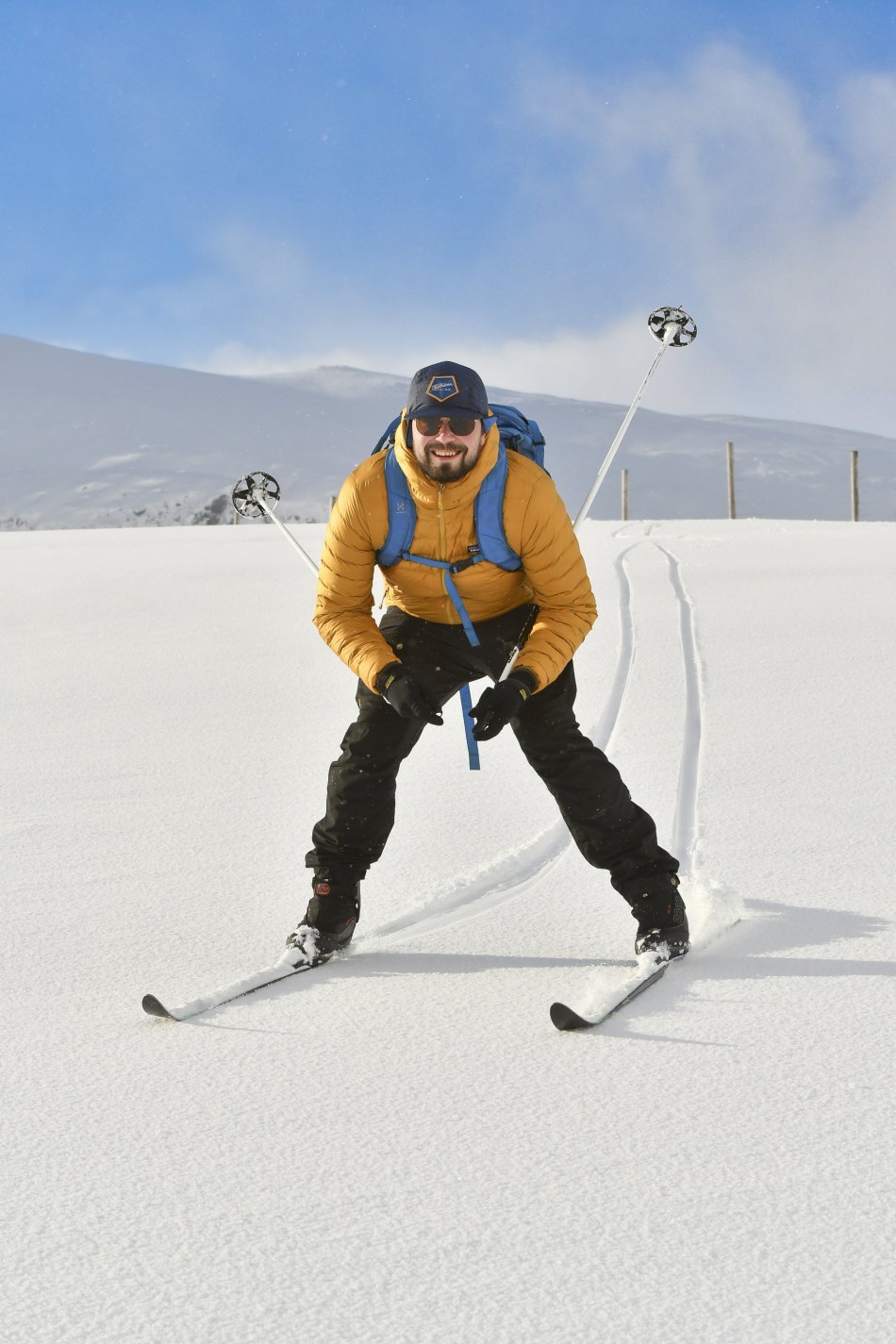 A man is smiling and back country skiing in Kilpisjärvi on a sunny day on beautiful white snow