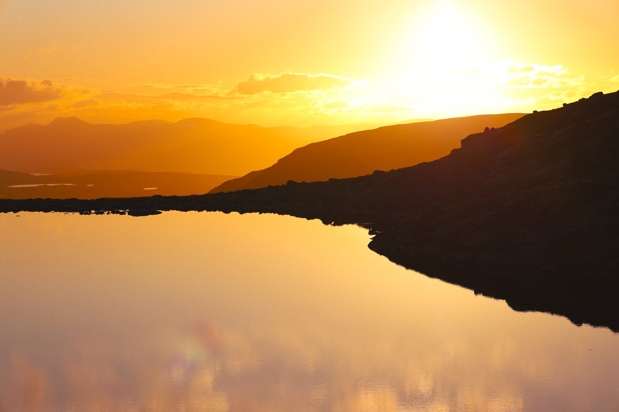 A calm mountain tarn on the slopes of Saana in Kilpisjärvi, glowing in the light of the Midnight Sun