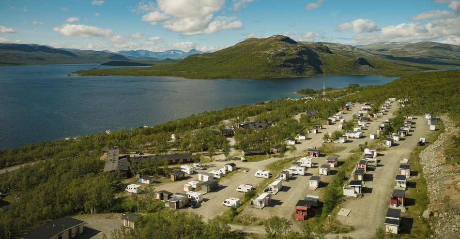 Kilpisjärven Retkeilykeskus from above on a sunny spring day. Lots of snow everywhere, you can see a read building and Malla fell and lake Kilpisjärvi
