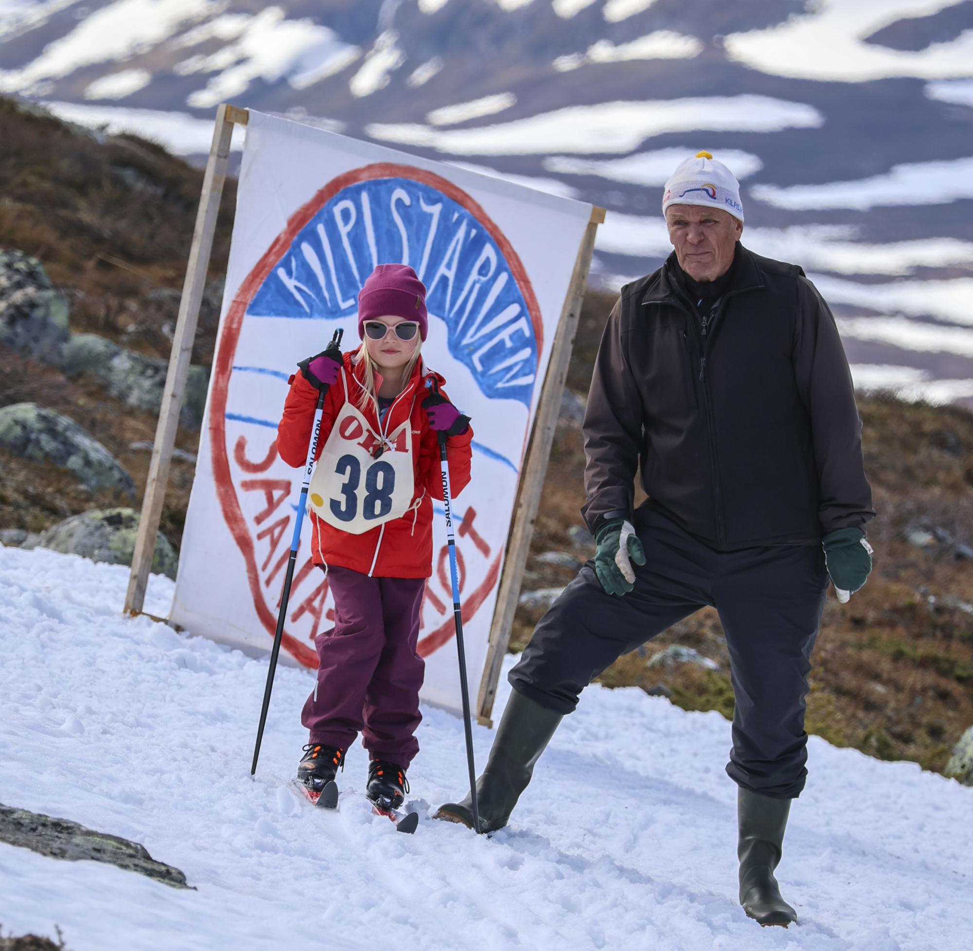 A girl dressed in ski gear, skis on her feet and poles in her hands, just about to be sent off at the Kilpisjärvi Midsummer Skiing event.