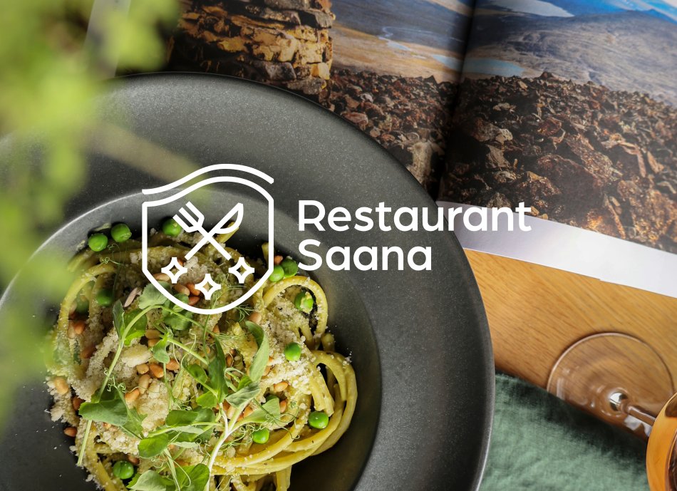 Colourful pea pasta dish and a magazine and glass of white wine at Restaurant Saana in Kilpisjärven Retkeilykeskus